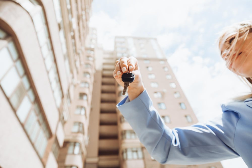 realtor-woman-holds-key-apartment-new-house-owner-property-makes-sale-buys-concept-real-estate-transaction-closeup